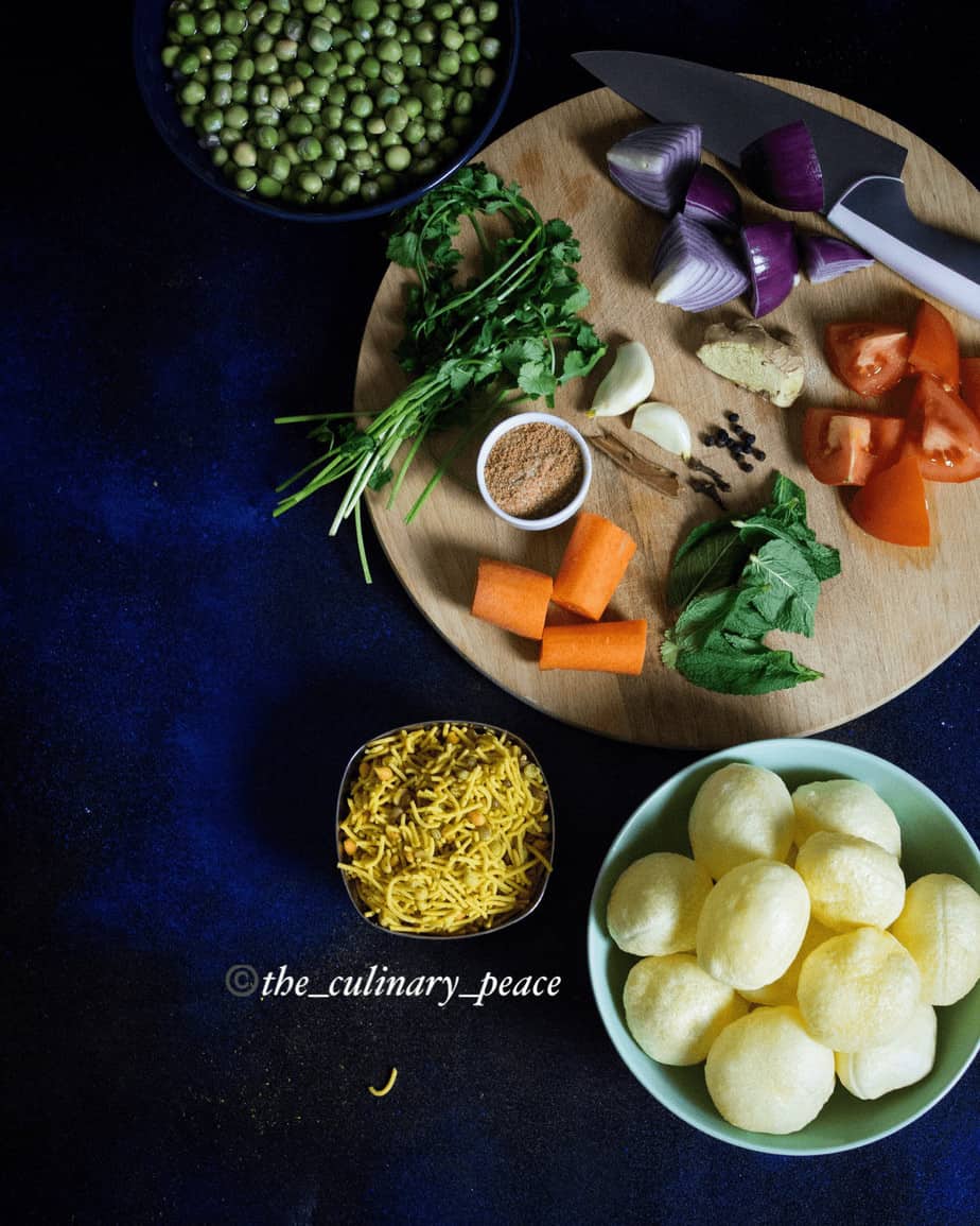Masala Puri recipe is an the authentic Bangalore style street food served with puris, masala, vegetables like carrot, peas, onions, tomato, coriander leaves and sev served on a grey plate against a dark background. How to make roadside masala puri recipe.
